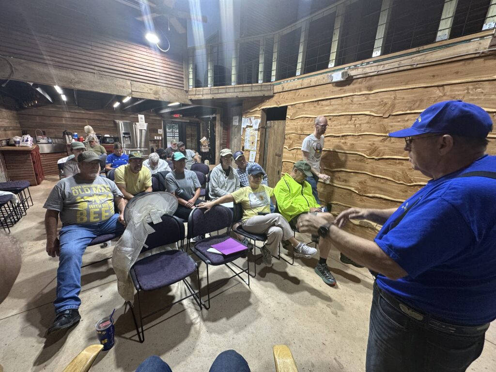 A group listens to a speaker in a rustic wooden room.